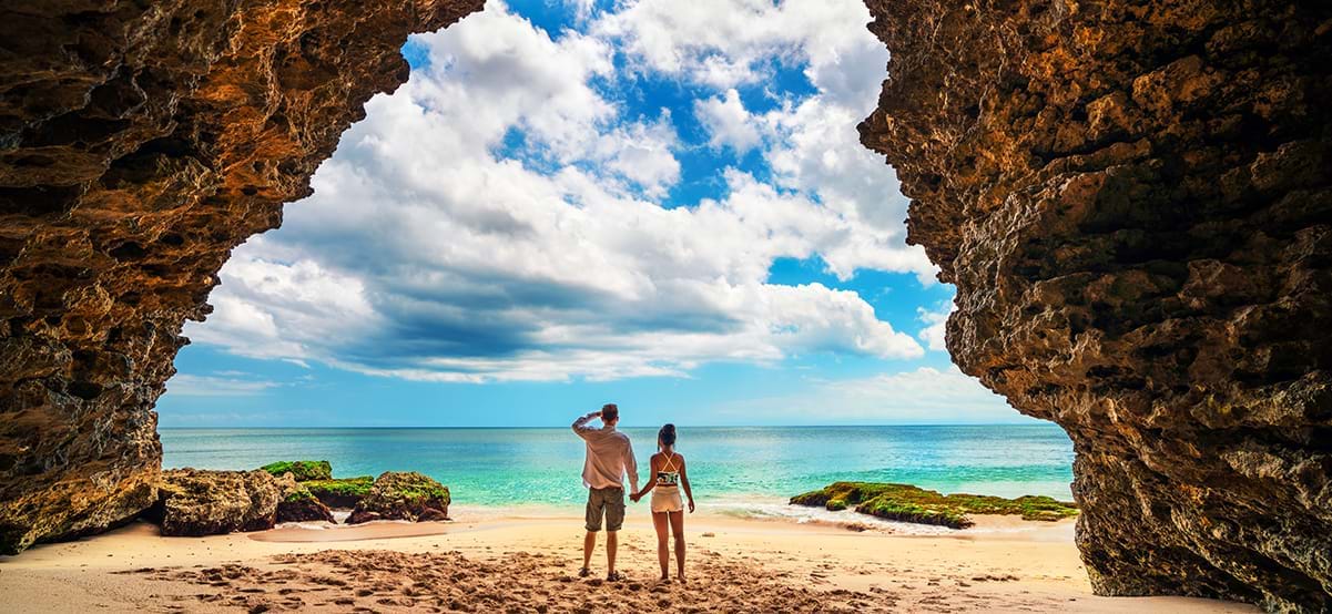 Couple at mouth of beach cave, Thailand